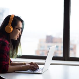 Frau an Laptop mit Kopfhörern